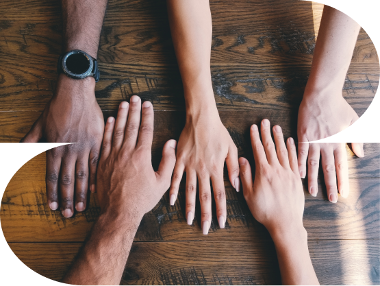 Vijf handen van diverse personen naast elkaar op een houten tafel, symboliserend de samenwerking, inclusiviteit en diversiteit die Hirehero biedt aan studenten en werkgevers.